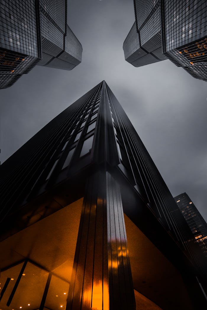 services-04 A low angle view of skyscrapers reaching into a moody night sky, showcasing modern architecture.
